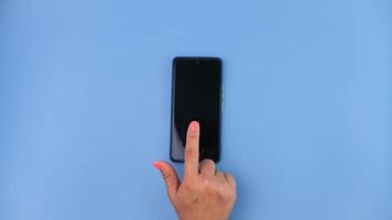 femmina mano clic su mobile Telefono schermo. vicino su di mano utilizzando smartphone su blu sfondo. foto