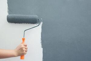 rullo spazzola la pittura, lavoratore pittura su superficie parete pittura appartamento, Restaurare con grigio colore dipingere. partire vuoto copia spazio bianca per Scrivi descrittivo testo accanto. foto