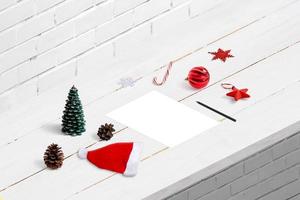 scrivere una lettera al concetto di babbo natale. un foglio bianco sulla scrivania, circondato da decorazioni natalizie. foto