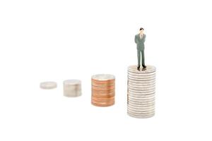 miniatura uomo d'affari in piedi su pila di nuovo tailandese baht monete, isolato su bianca sfondo. attività commerciale e finanza concetto. foto