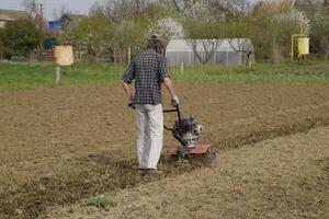 un' uomo aratri un' timone nel il giardino. primavera coltivazione di il giardino foto