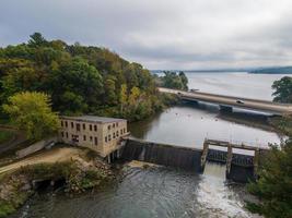 Vista aerea della diga con ponte sul fiume al lago in autunno timoneria storica con strada di ghiaia attiva sfioratore foto