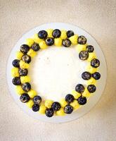compleanno bianca e giallo torta con mirtilli su un' bianca piatto su un' leggero sfondo, disposizione foto