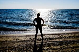 silhouette di un' bellissimo ragazza figura su il sfondo di il mare a tramonto foto