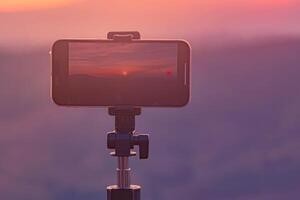 un' smartphone è registrazione il sole ambientazione al di sopra di un' montagna gamma. foto