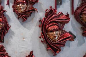 collezione di rosso veneziano maschere visualizzato nel debolmente illuminato interno nel Venezia, Italia foto