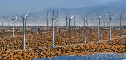 rinnovabile energia vento azienda agricola nel arido deserto paesaggio con blu cielo, montagne, e scarso vegetazione foto