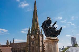 Gotico Chiesa e statua contro moderno orizzonte nel Birmingham, UK foto