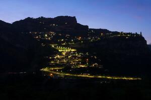 notte Visualizza di un' montagna villaggio con raggiante lanterne su un' scogliera foto