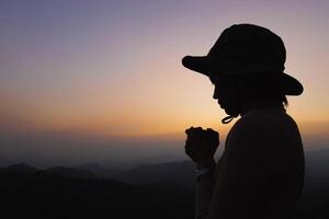 silhouette di un' donne è preghiere per Dio su il montagna. preghiere mani con fede nel religione e credenza nel Dio su benedizione sfondo. energia di speranza o amore e devozione. foto