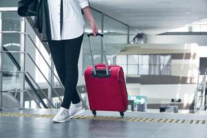 donna viaggiatore con bagaglio nel il aeroporto o treno stazione, gambe e valigia avvicinamento foto