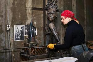 donna metallo artista a opera nel laboratorio utilizzando taglio del metallo sega foto