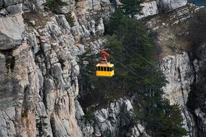 cabina di il aereo tram si sposta contro il sfondo di un' ripido roccioso scogliera foto