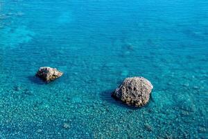 marino sfondo, trasparente blu costiero litorale al di sopra di corallo scogliera e Due rocce salire sopra il acqua foto