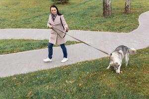 giovane donna passeggiate con un' cane chi trovato qualcosa su il prato foto