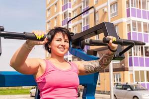 giovane donna scuote sua tricipiti utilizzando strada il petto stampa Palestra macchina foto