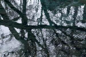 acqua superficie di il stagno su un' piovoso giorno con cielo e rami di spoglio alberi riflessa nel esso foto