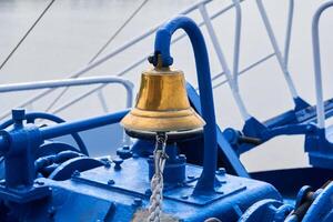ottone campana su il ponte di prua di un' nave nel nuvoloso leggero foto