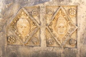 cancellato a metà tagliato a pietra maschere su il rovine di un' edificio nel il antico città di mira, tacchino foto