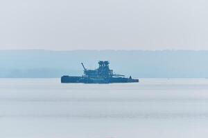 galleggiante sabbia estrazione pianta su il fiume nel il mattina nebbia foto