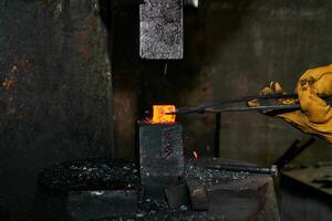 femmina mani processi un' rosso caldo pezzo in lavorazione con un' energia martello foto