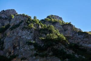 ripido montagna sporgenze, coperto di vegetazione con vegetazione, contro il cielo foto