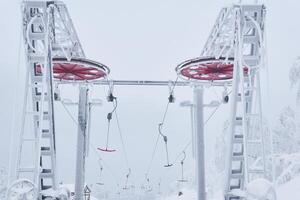 superiore stazione di il sciare sollevamento su un' innevato cima tra gelido alberi foto