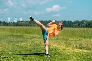 adolescenziale ragazza nel casuale Abiti formazione karatè kata all'aperto, esegue il uro mawashi geri gancio calcio foto