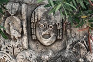 antico tagliato a pietra maschera tra vegetazione nel il rovine di il antico città di mira, tacchino foto