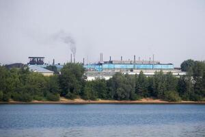 industriale paesaggio con un' fabbrica su il banche di il fiume foto