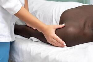 donna massaggiatore fare massaggio di spalla la zona di mano per nero uomo foto