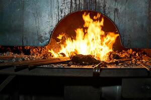 maniscalco forno con ardente fuoco con billette riscaldamento su esso foto
