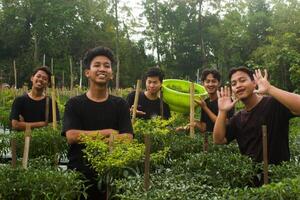 5 giovane asiatico agricoltori siamo ordinamento peperoncini per raccogliere nel il giardino. durante il giorno utilizzando tradizionale utensili e nero magliette. smilling foto