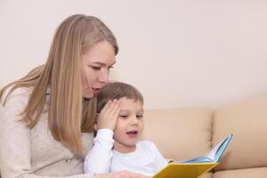 donna lettura libro per bambino in casa foto