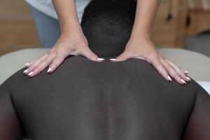 donna massaggiatore fare massaggio di spalla la zona per nero uomo foto