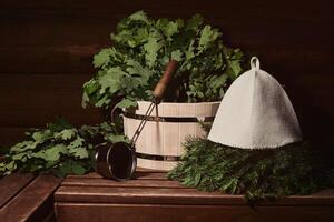 interno di un' tradizionale vapore sauna banya con di legno vasca, acqua mestolo, cappello e bagno scope su un' panchina foto