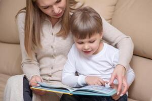 donna lettura libro per bambino in casa foto