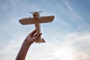 bambino Tenere un' di legno aereo modello alto nel il cielo foto