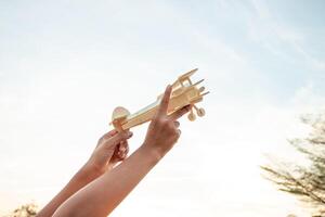 bambino Tenere un' di legno aereo modello alto nel il cielo foto