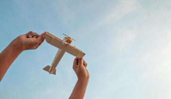 bambino Tenere un' di legno aereo modello alto nel il cielo foto