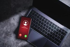 smartphone ricevente indesiderato chiamata mentre riposo su il computer portatile. spam, truffa, phishing e frode concetto. sicurezza tecnologia. foto