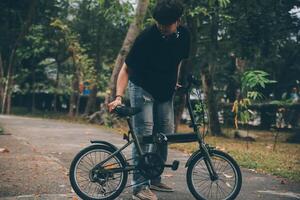 giovane bello barbuto uomo assunzione un' rompere mentre in viaggio il città con il suo bicicletta utilizzando il suo digitale tavoletta guardare lontano pensieroso foto