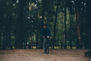 giovane bello barbuto uomo assunzione un' rompere mentre in viaggio il città con il suo bicicletta utilizzando il suo digitale tavoletta guardare lontano pensieroso foto