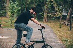 giovane bello barbuto uomo assunzione un' rompere mentre in viaggio il città con il suo bicicletta utilizzando il suo digitale tavoletta guardare lontano pensieroso foto