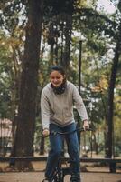 contento asiatico giovane donna camminare e cavalcata bicicletta nel parco, strada città sua sorridente utilizzando bicicletta di trasporto, eco amichevole, persone stile di vita concetto. foto