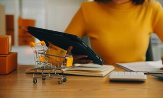 giovane donna piccolo imprenditore shopping online a casa. prendere nota degli ordini dei clienti con telefoni cellulari. piccolo imprenditore o concetto di stile di vita freelance. foto