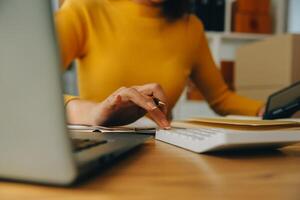 giovane donna piccolo imprenditore shopping online a casa. prendere nota degli ordini dei clienti con telefoni cellulari. piccolo imprenditore o concetto di stile di vita freelance. foto