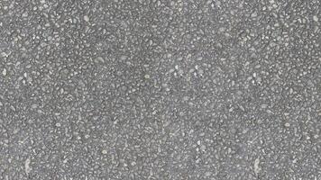 ai generato un' uniforme grigio asfalto struttura fatto su di piccolo pietre e ciottoli nel variando occhiali da sole di grigio piace strada struttura sfondo foto