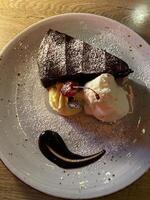 piatto di cioccolato torta con crema, un' ciliegia e glassatura zucchero su superiore foto