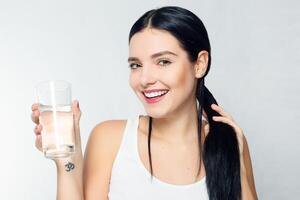 sorridente giovane donna con bicchiere di acqua foto